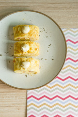 Omelette roll on beige plate over colorful paper