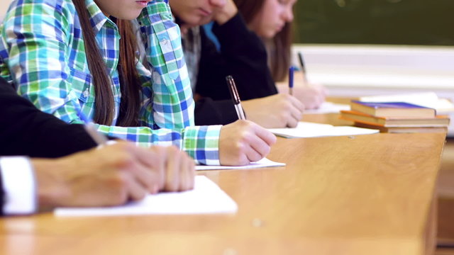 Row of students hands  writing task on copybooks