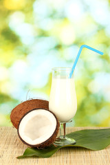 glass of coconut milk and coconuts on green background close-up