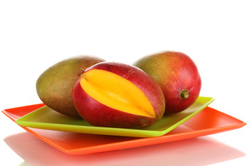 Ripe appetizing mango on red plate isolated on white
