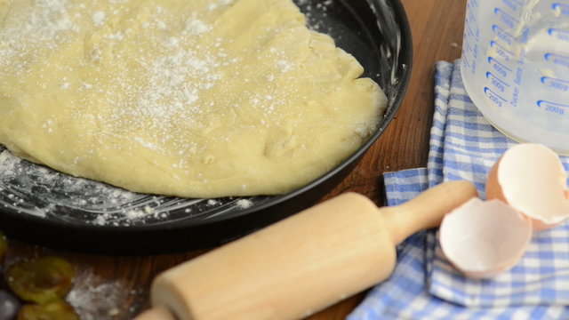 Hefeteig und Nudelholz wird mit Mehl bestreut