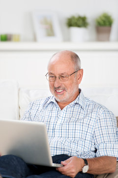 älterer mann arbeitet zuhause am laptop