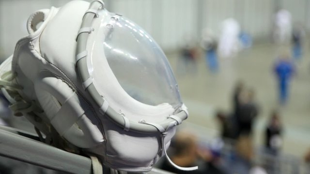 White helmet of fighter KUDO against sportsmen training in hall
