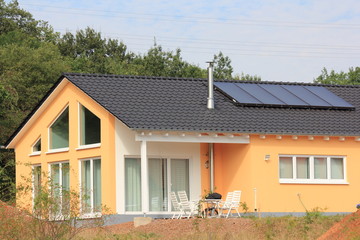 gelber Neubau mit Solaranlage