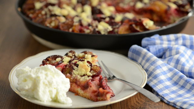 Schlagsahne wird auf einen Teller mit Pflaumenkuchen getan