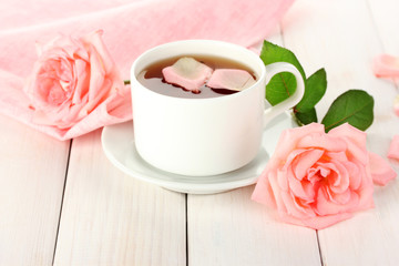 cup of tea with roses on white wooden table