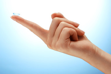 contact lens on finger on blue background