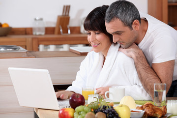 Couple eating breakfast together whilst browsing the internet