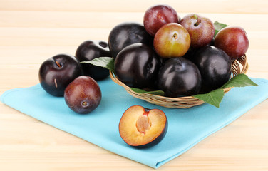 Rip plums on basket on wooden table