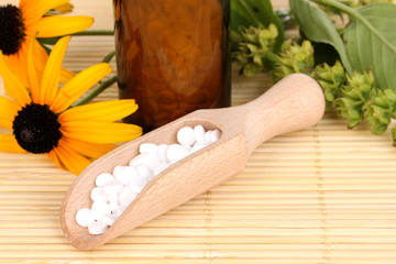 medicine bottle with tablets and flowers on bamboo mat