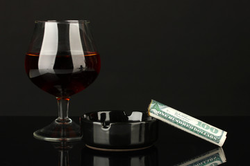 Cigar of the 100 dollar bill and an ashtray and glass of brandy