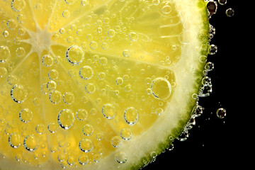 slice of lime in the water with bubbles, on black background