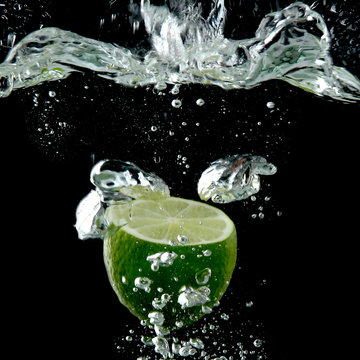 half of lime in the water on black background