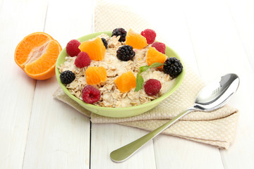 tasty oatmeal with berries and fruits, on white wooden table