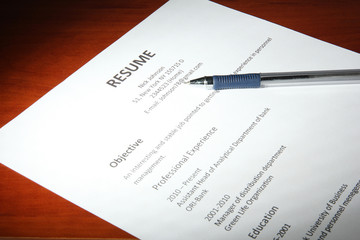 Closeup of resume with pen on wooden table