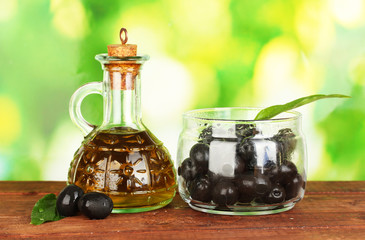 Olive oil small decanter on green background close-up