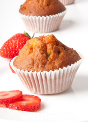 Strawberry muffin on a white plate with a fresh strawberry 