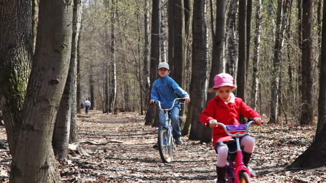 sister and brother ride their bicycles at park