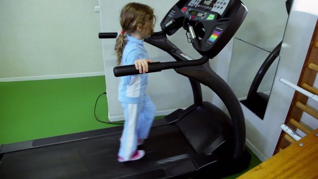 girl walks by treadmill and looks to panel
