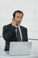 Businessman using a mobile telephone and laptop computer