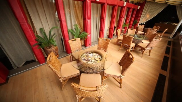 Wicker chairs and tables stand in hall of restaurant