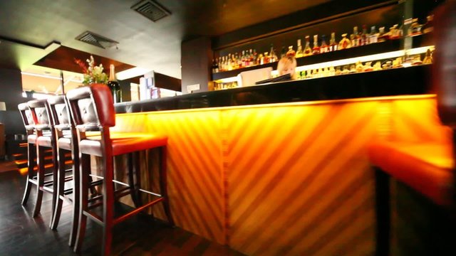 Chairs in bar stand along long bar counter