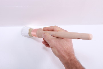 Closeup of a man cutting in a corner with white paint