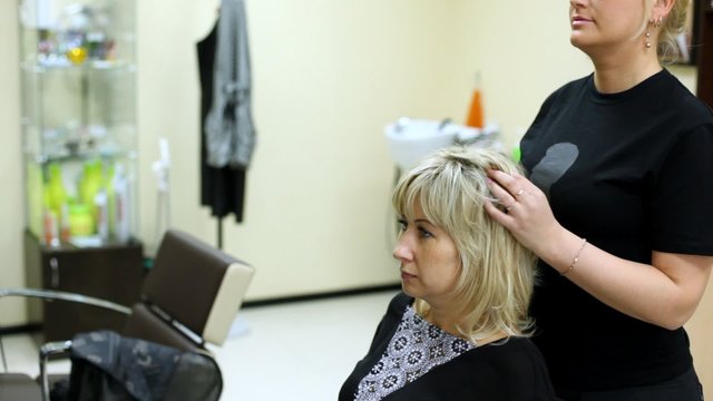 woman sits in hairdressing salon in seat to make hairdress