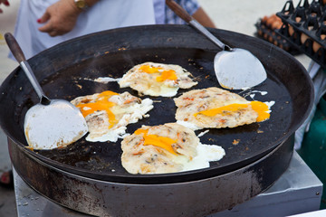 Oysters fried in egg batter being cooked in a pan