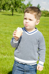 Мальчик с мороженым в руке стоит в парке