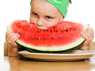 little boy eating a watermelon at a table