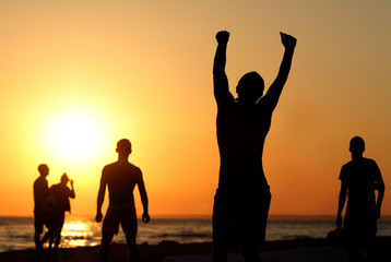 Fototapeta premium Silhouette of a happy person on the beach in summer. Group of friends enjoying vacation together
