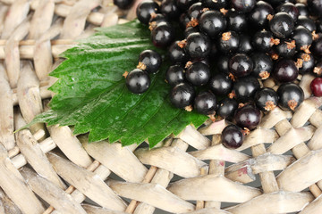 Fresh black currant on wicker mat close-up