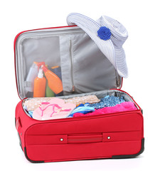 Suitcase with summer clothes, a hat and suntan isolated on