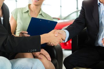 Handschlag im Autohaus vor Auto