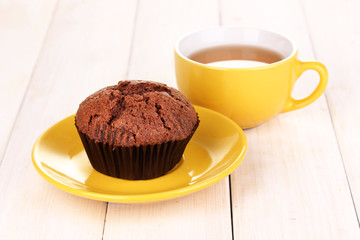 Fresh muffin with tea on wooden background
