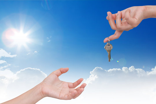 Human hand with key and blue sky