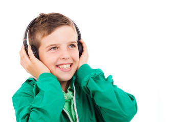 Young casual boy listening to music on headphones against white