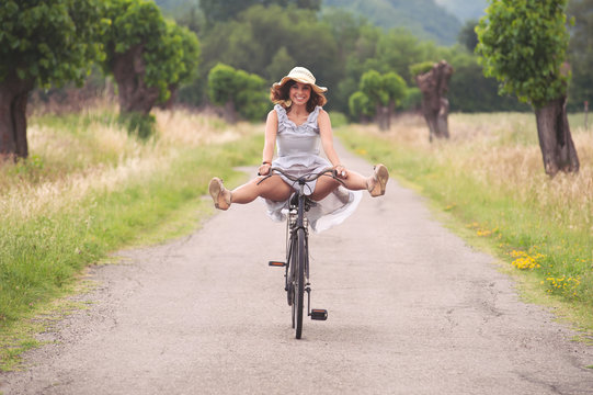 Pretty Young Woman Riding Bike In A Country Road.