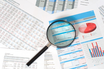 magnifying glass over financial reports