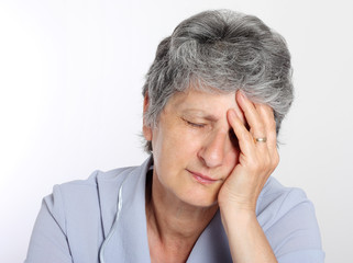 Portrait of a sad senior woman holding her head in pain