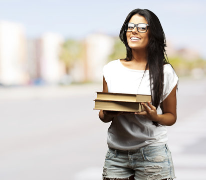 portrait of young girl holding books at crowded city