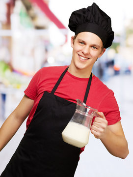 portrait of young cook man holding milk jar at street