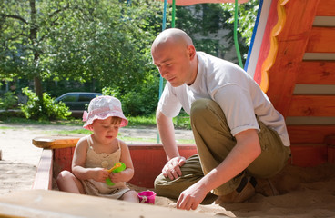 father with  toddler playing  in sandbox