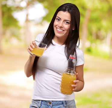 portrait of young girl drinking orange juice against a nature ba