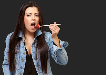 Fototapeta premium Portrait Of A Female Eating Strawberry With Chocolate Sauce