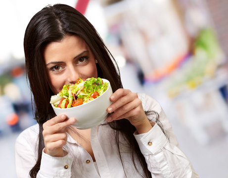 portrait of young woman holding a fresh salad at street