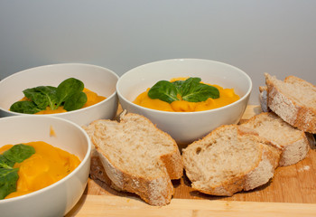 Bowls of pumpkin soup with bread rolls