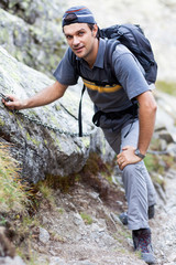 Young man hiking on difficult mountain trail