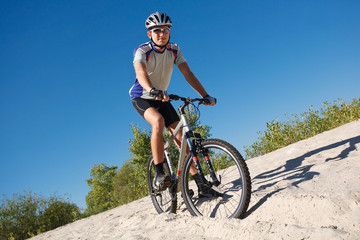 Fototapeta premium male cyclist riding a bike stopped rolling on the sand